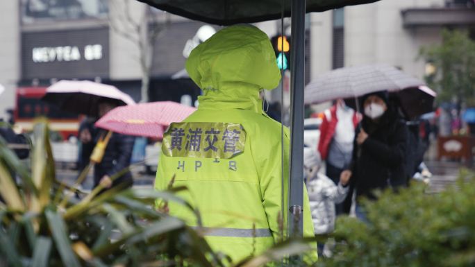 南京路下雨行人撑伞过马路交警站岗红绿灯
