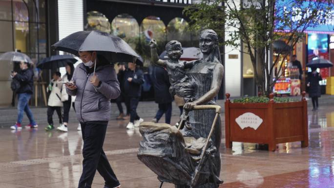 上海南京路下雨天雕像雨中孤单铜像行人忙碌