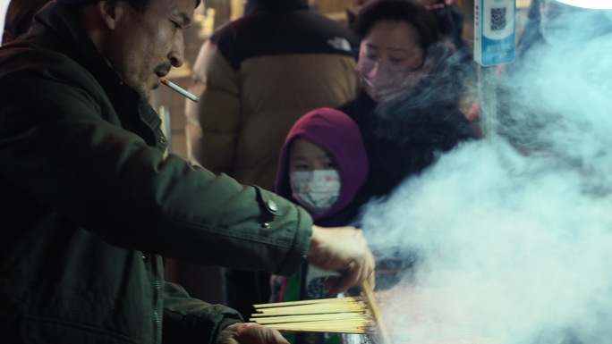 抽烟的新疆人烧烤羊肉串