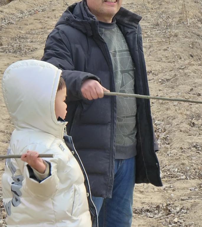 竖版冬天爷爷带着孙子在田地里游玩散步