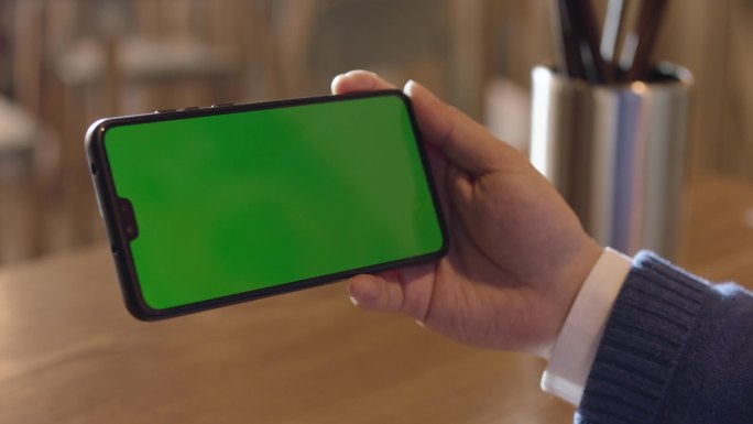 男性拿着绿色屏幕的手机