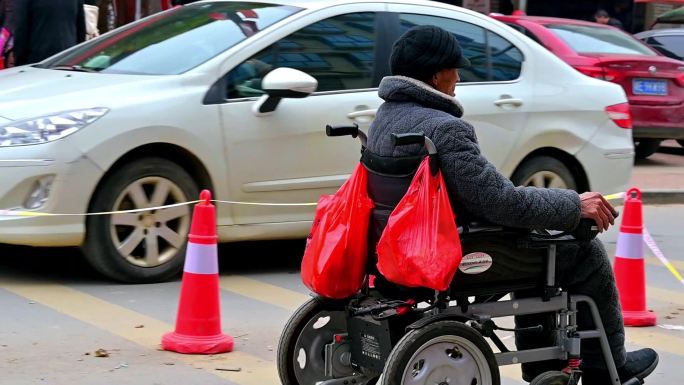 坐电动轮椅的老爷爷穿梭在街上