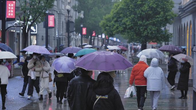 城市步行街逛街打伞的人群