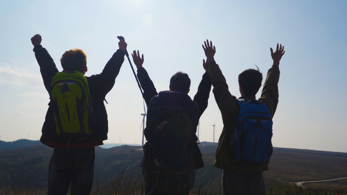 团队挥手背影成功登顶山顶举手呐喊庆祝胜利