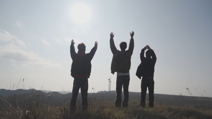 团队成功登顶山顶挥手呐喊庆祝胜利团队背影