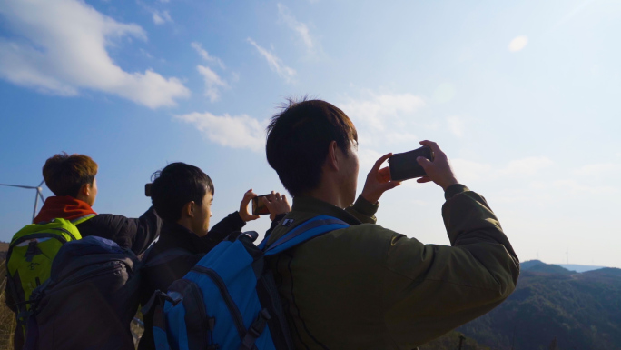 成功登顶山顶拍照团队逆光背影山顶眺望远方