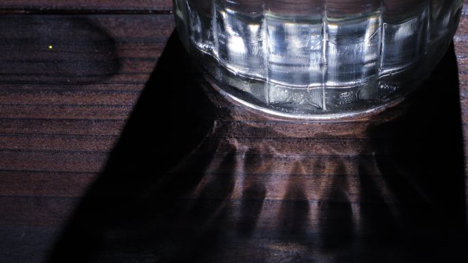 玻璃杯的光影在桌面上移动