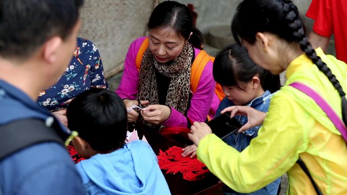 乡村母亲教孩子们剪纸游客参观