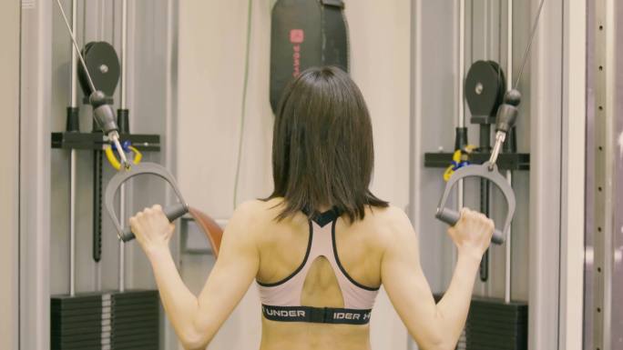 肌肉女健美运动员在健身房使用健身机锻炼