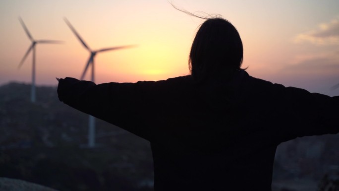 女青年站在山顶看日出拥抱阳光看夕阳日落