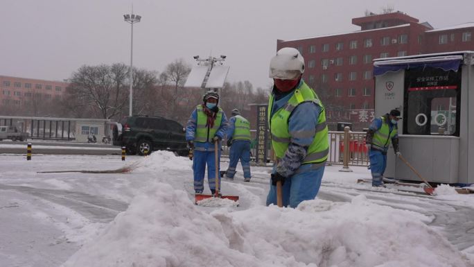 环卫工人雪天清理广场上的积雪