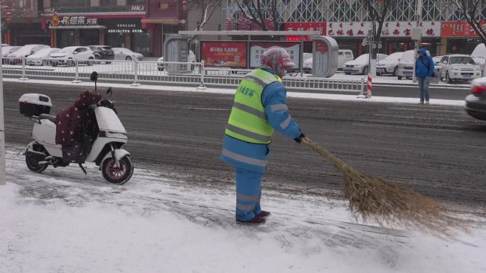 下雪天环卫工人冒雪清理路边积雪