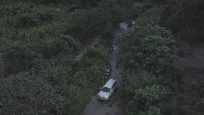 白色汽车在森林中的泥泞的道路上