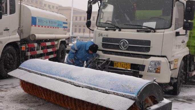 下雪天环卫司机检查除雪车滚刷准备除雪作业