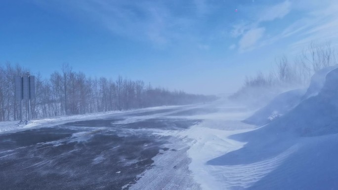 寒冬国道风吹雪白毛风行驶中的汽车