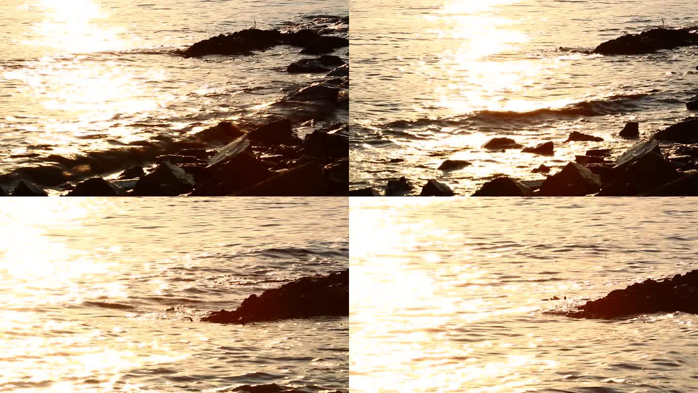 夕阳下海浪拍打礁石