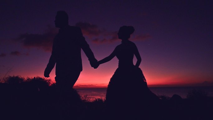 一对情侣牵手漫步在海边的剪影