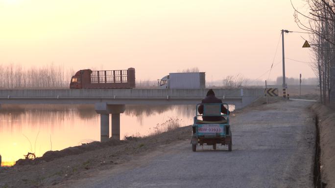 乡村傍晚一位老人骑着电动三轮车远去背影2