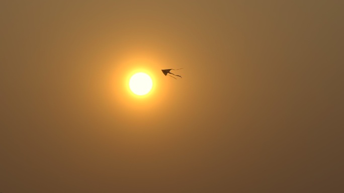 黄昏风筝穿过太阳飞翔降落