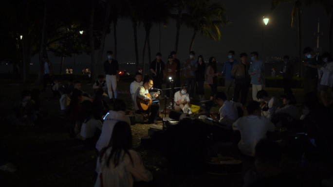 夜晚男子吉他弹唱观众围观