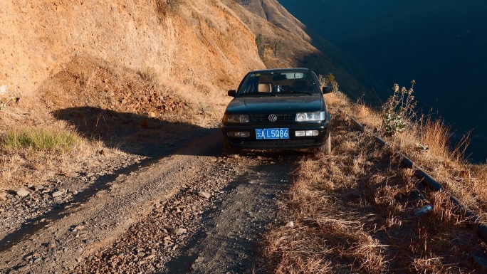 云南贫困山区土石路上黑色轿车