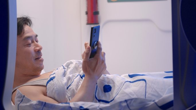 中年男人躺在床上玩智能手机