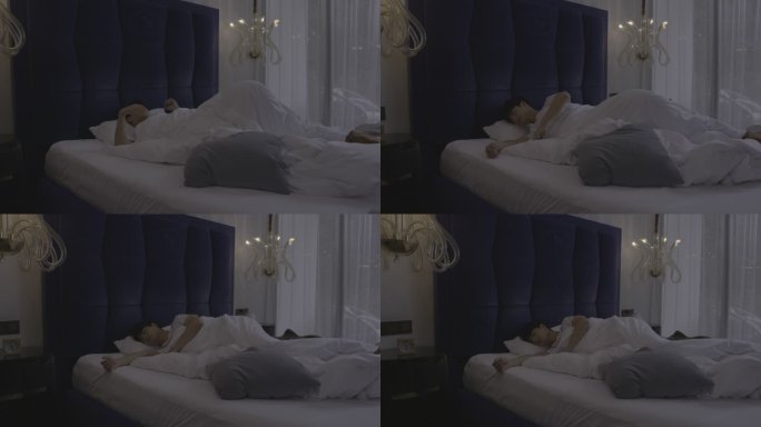 俯视图：年轻男子晚上睡觉时在床上翻身