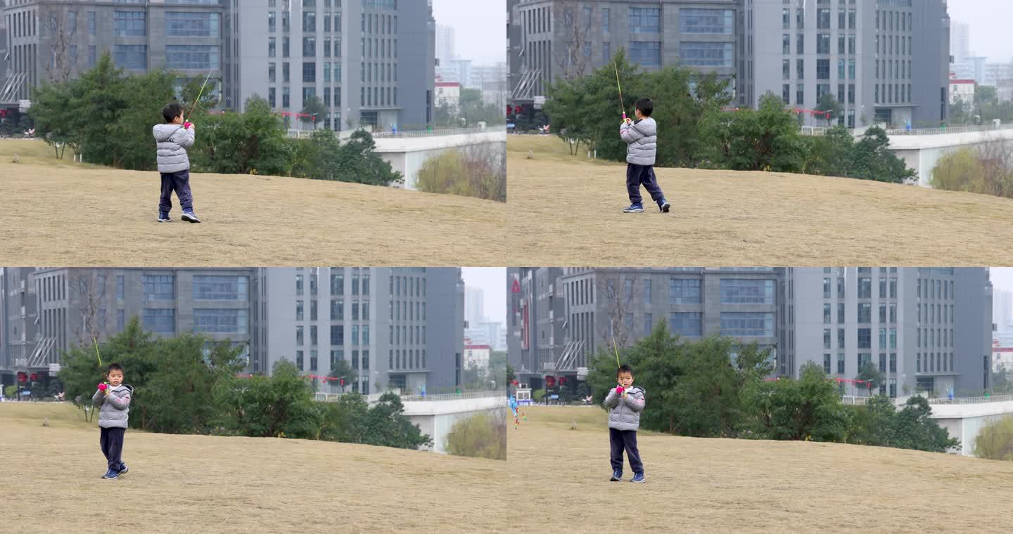 小男孩在城市公园草地上奔跑着放风筝