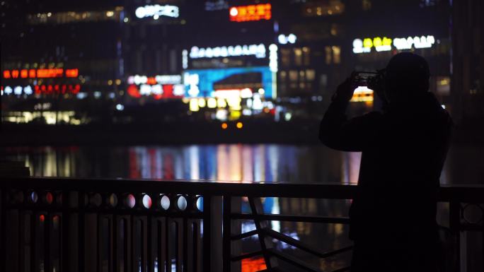 在河边用手机拍夜景的男人