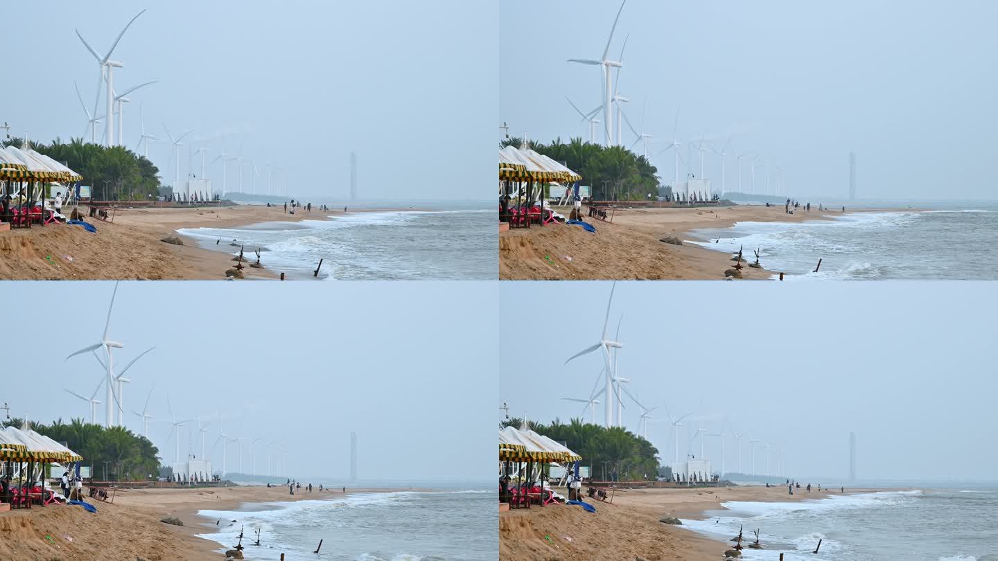 海南省东方市鱼鳞洲沙滩的游客与风力发电机