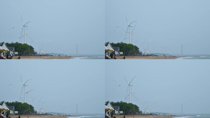 海南省东方市鱼鳞洲沙滩的游客与风力发电机