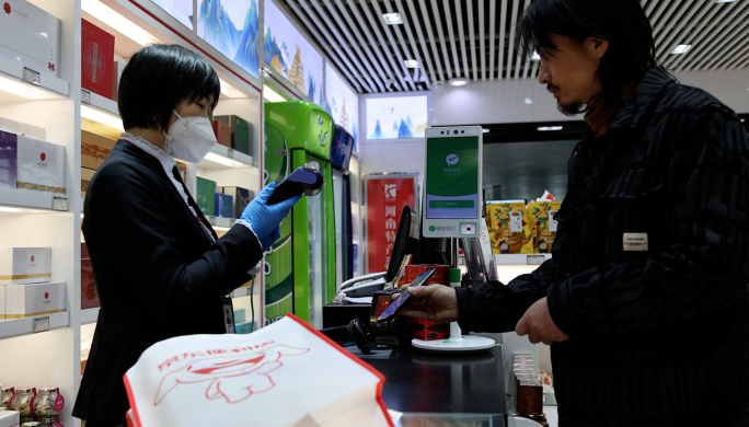 年轻人在机场超市购物 付款码手机扫码付款