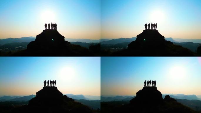 一群人登顶山峰一群人站在山顶看日落团队光