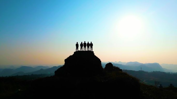 一群人站在山顶眺望日落美景青年登山追梦人