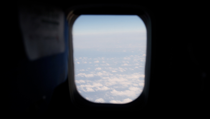 透过飞机窗口看蓝天白云 云层之上的飞行