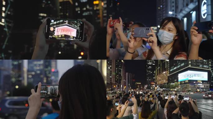 拿手机观看手机拍照自拍繁华市中心夜景人群