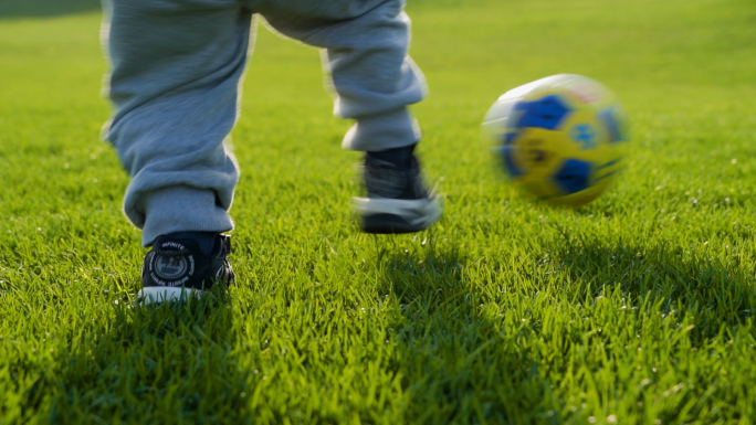 小孩草地踢足球特写阳光男孩美好童年户外