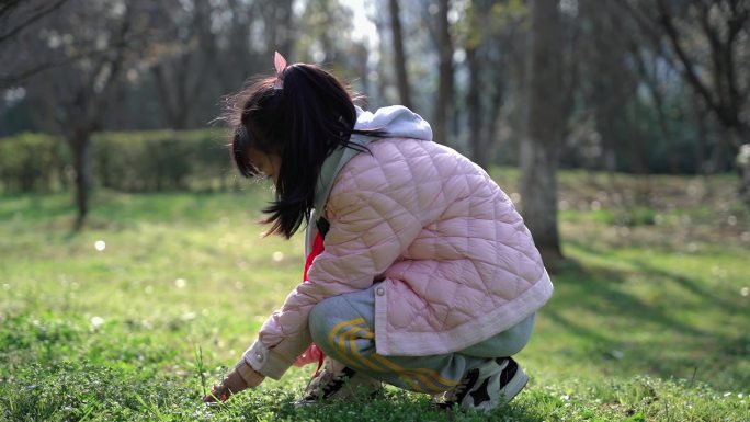 冬日暖阳下在草地上近距离抚摸小草的女孩子