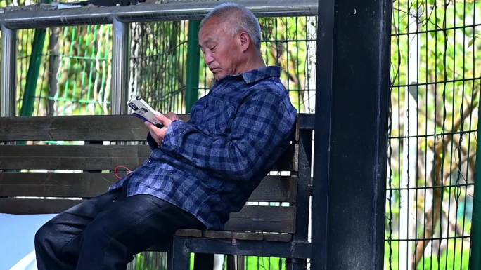 孤独老人公园里看着手机-老年人用智能手机