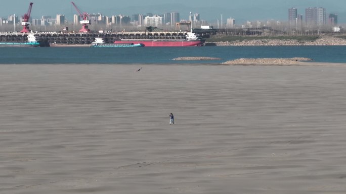 女生在长江边广袤的沙滩上奔跑放风筝航拍