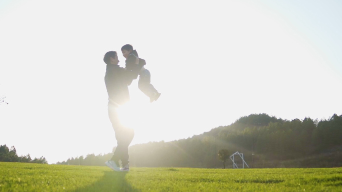 小孩拿着飞机草地奔跑爸爸拥抱小孩父亲肩膀