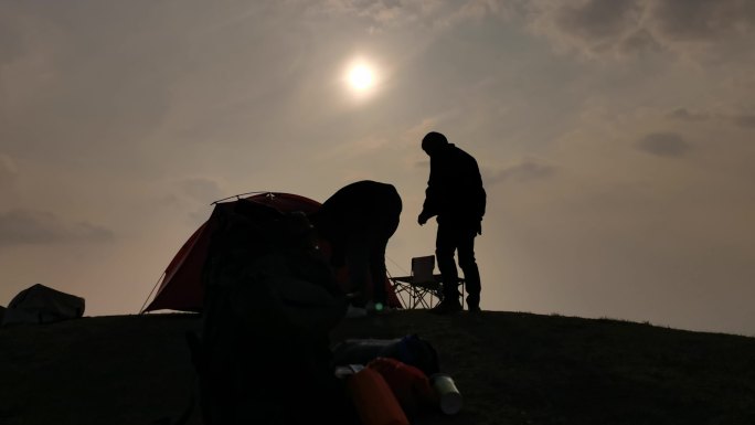 夕阳下安装帐篷剪影