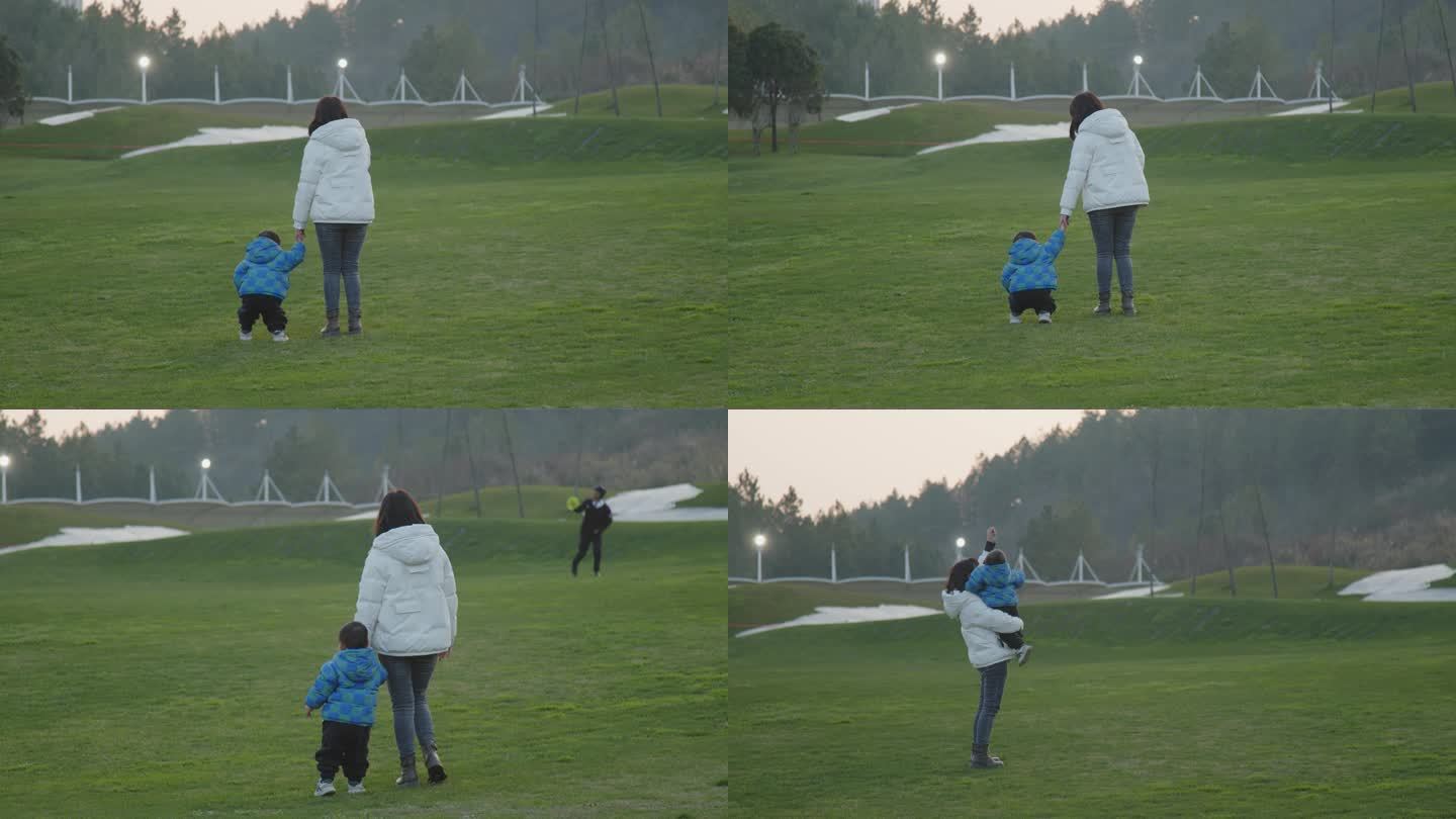 母亲陪孩子在公园草坪上自由玩耍