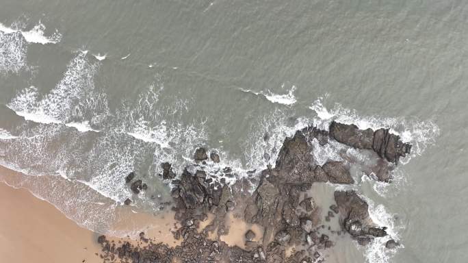 大海俯拍礁石浪花海水拍打礁石阴天海水浑浊