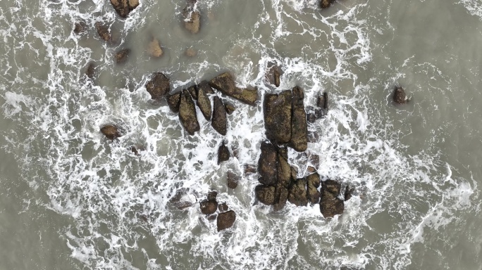 大海俯拍礁石浪花海水拍打礁石阴天海水浑浊