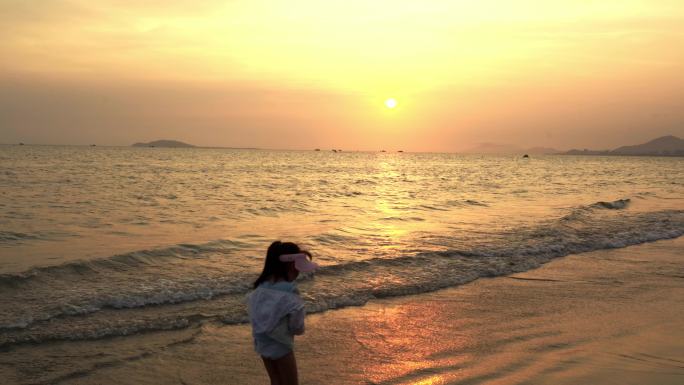 海南三亚湾日落一个小女孩在踏浪