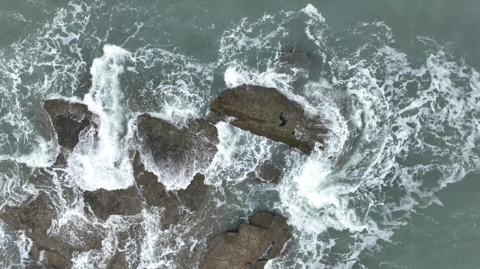 大海俯拍礁石浪花海水拍打礁石阴天海水浑浊