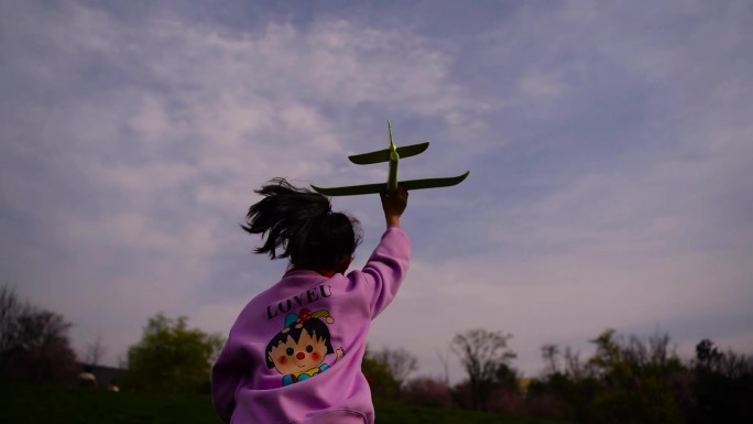 小女孩拿着飞机模型 草地奔跑