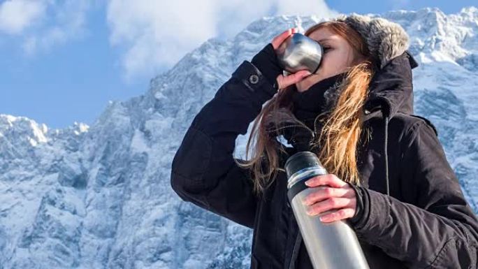 女人在雪山的热水瓶里喝酒