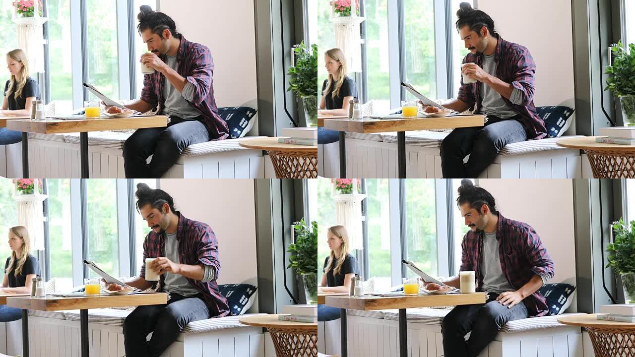 男子在咖啡馆喝咖啡时读报纸